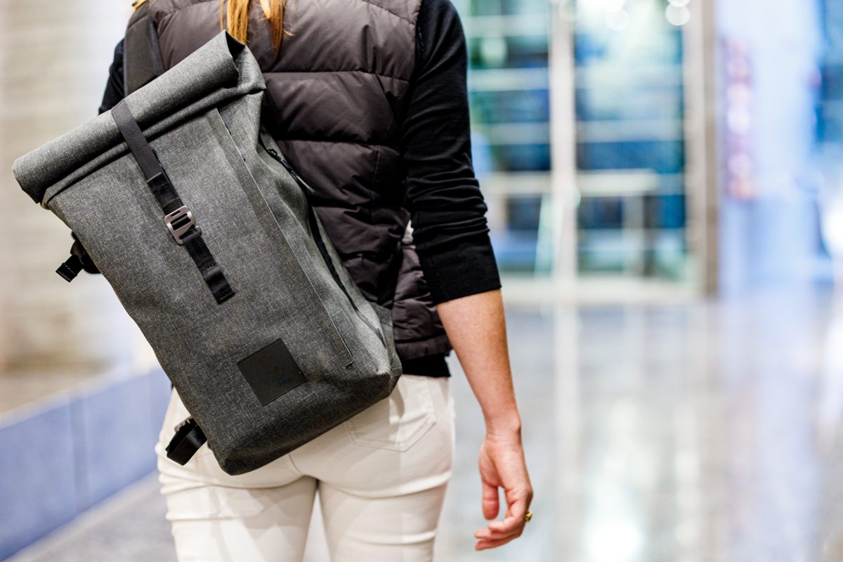 f-stop Dyota 11 liter sling camera bag in the Battleship Grey color option being worn by a female model in an urban/office environment