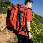 f-stop Tilopa 50 liter DuraDiamond® camera backpack in the Magma Red color option being worn with a landscape in the background