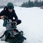 Tilopa 50 L Cypress Camera Pack on the Ground in the Snow showing Ambassador Harald Whistler exchanging his camera