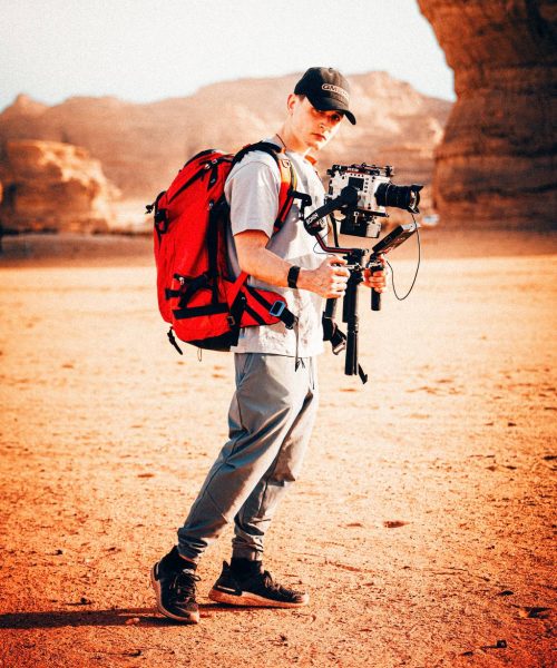 f-stop Ambassador Nick Leavesley with his Tilopa 50 liter Duradiamond® camera backpack in the Magma Red color option and carrying his RED V-Raptor camera system